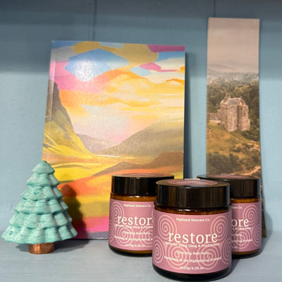 Jars labeled 'restore' with a decorative tree and landscape painting on a gray surface