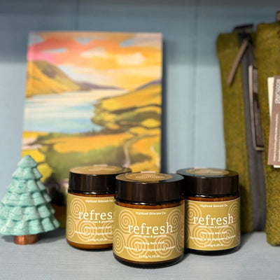 Three jars labeled 'refresh' with a scenic painting and decorative items in the background.