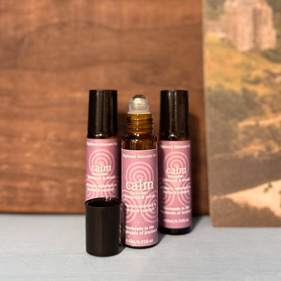 Three bottles of 'calm' skincare serum with pink labels on a neutral background